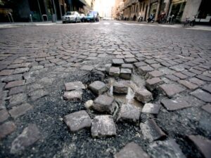 Milano va a pezzi: buche, marciapiedi sbriciolati e dislivelli pericolosi. L’allarme delle associazioni
