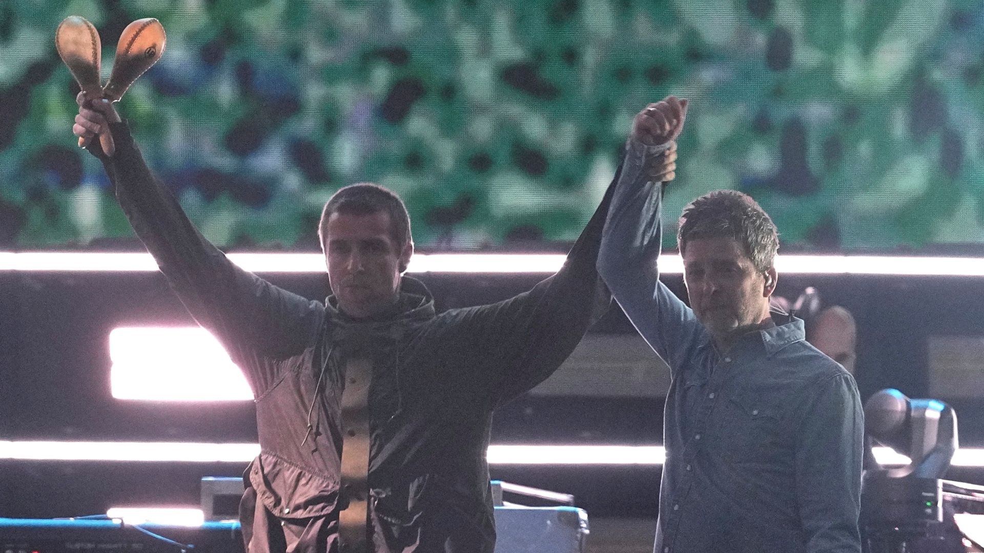 I fratelli Gallagher si danno il cinque e si abbracciano quando gli Oasis si riuniscono sul palco dopo 16 anni